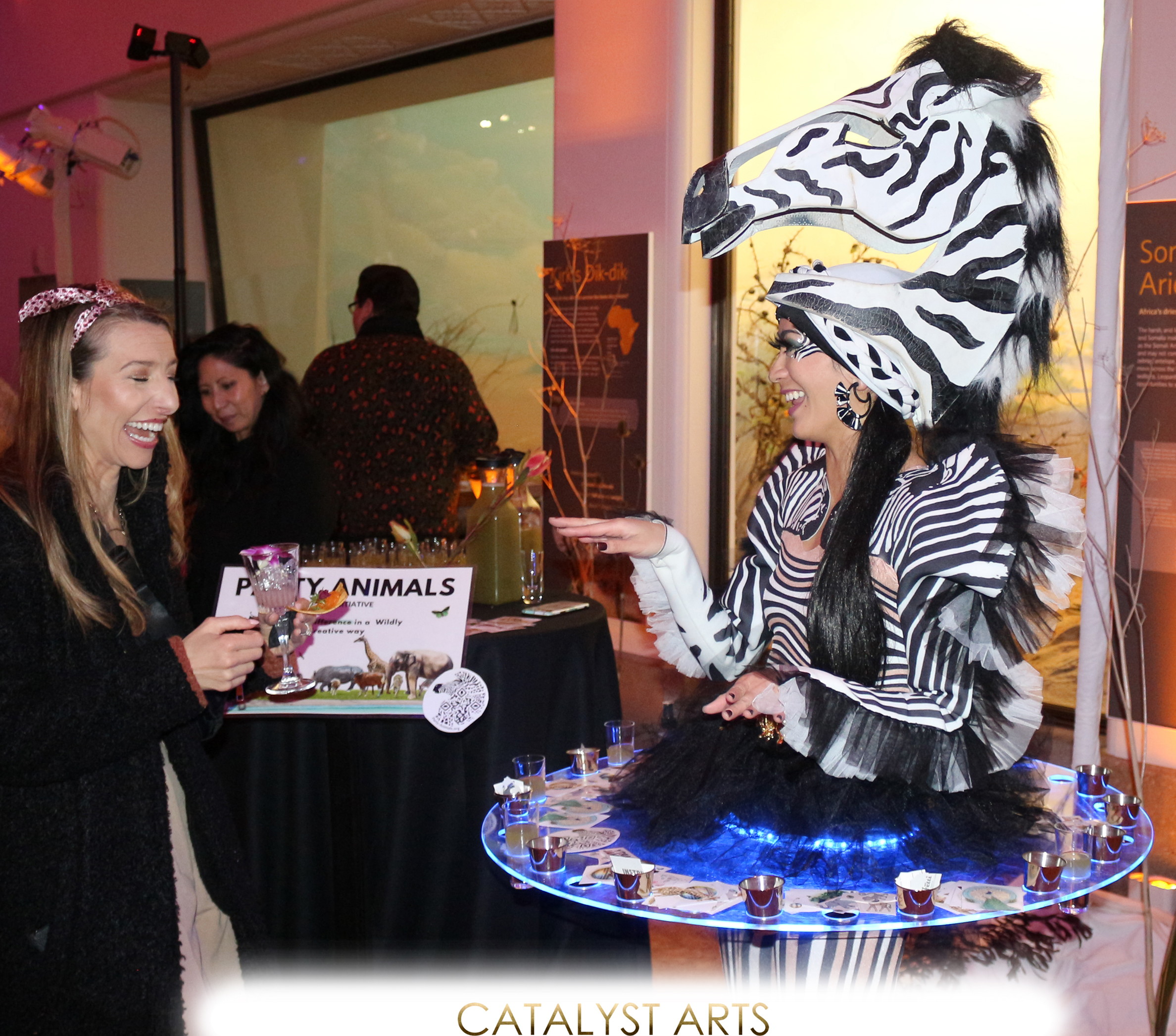 Zebra hostess in LED shot skirt playing games with guests for a Party Animals pop up at an event at California Academy of Sciences. 