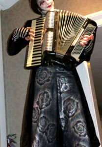 Stiltwalker holding an accordion