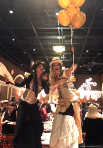 Steampunk stilt walker duo holding a yellow balloon